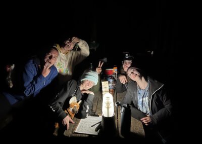 5 people making goofy faces at the camera in the dark with their lights lit from lanterns